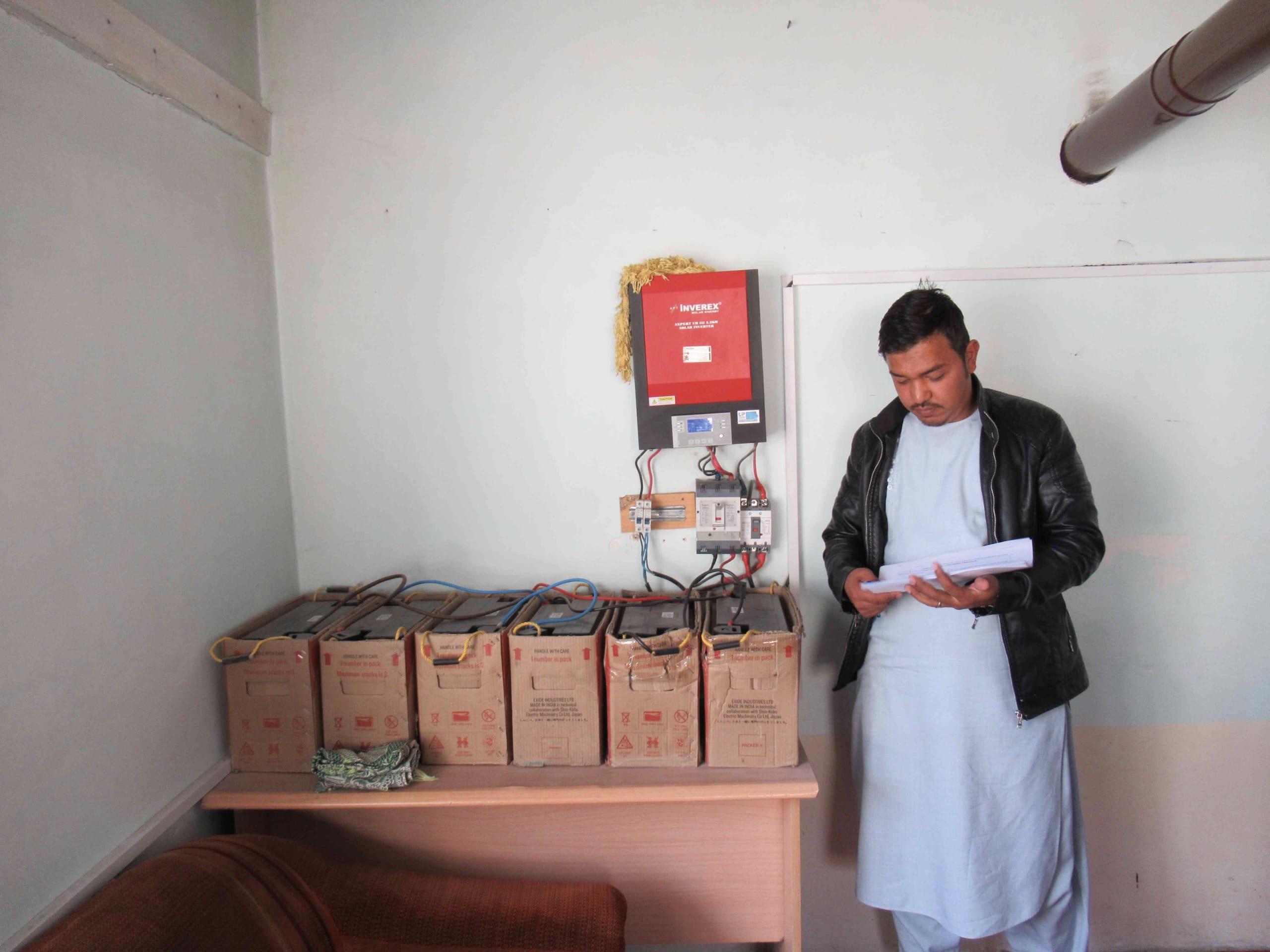 Maintenance of the inverter (red box) and the batteries (six boxes on the table)